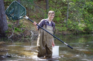 Brad Carlson uses a dipnet to sample a pond community.
